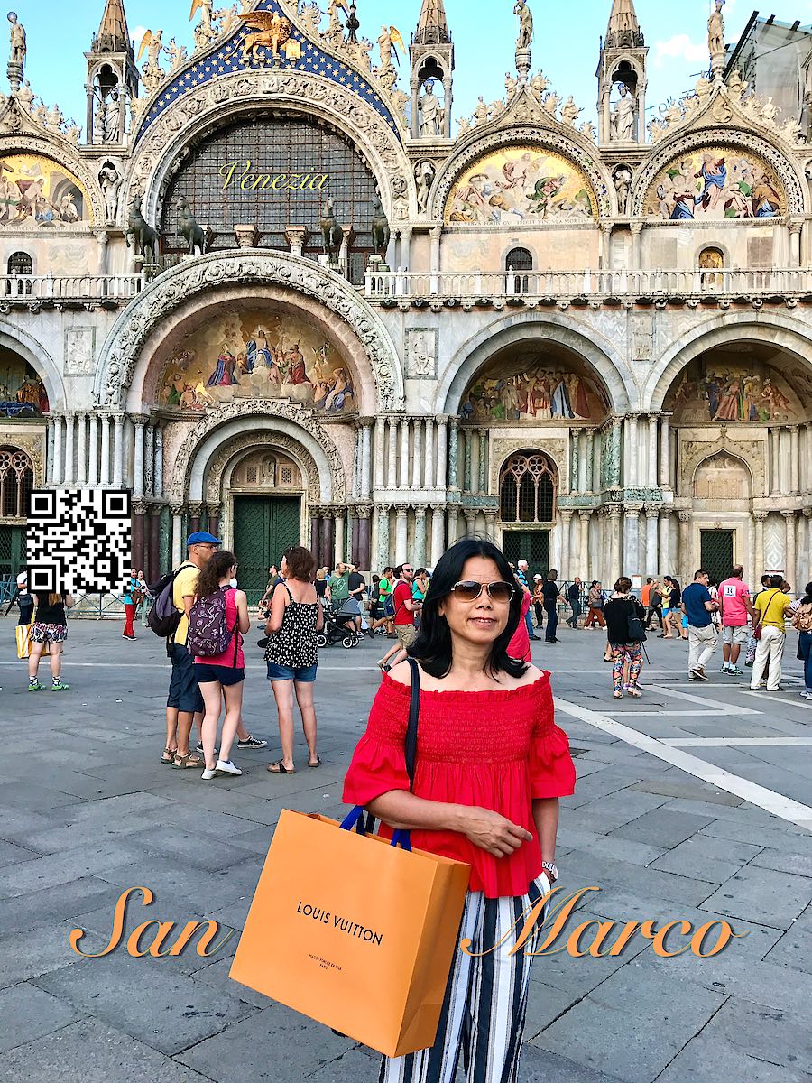 Italy Venice woman in red holding a Louis Vuitton bag at Piazza San Marco and the basilica